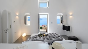 Un dormitorio moderno con cama, mesita de noche y vista al mar por una puerta abierta.