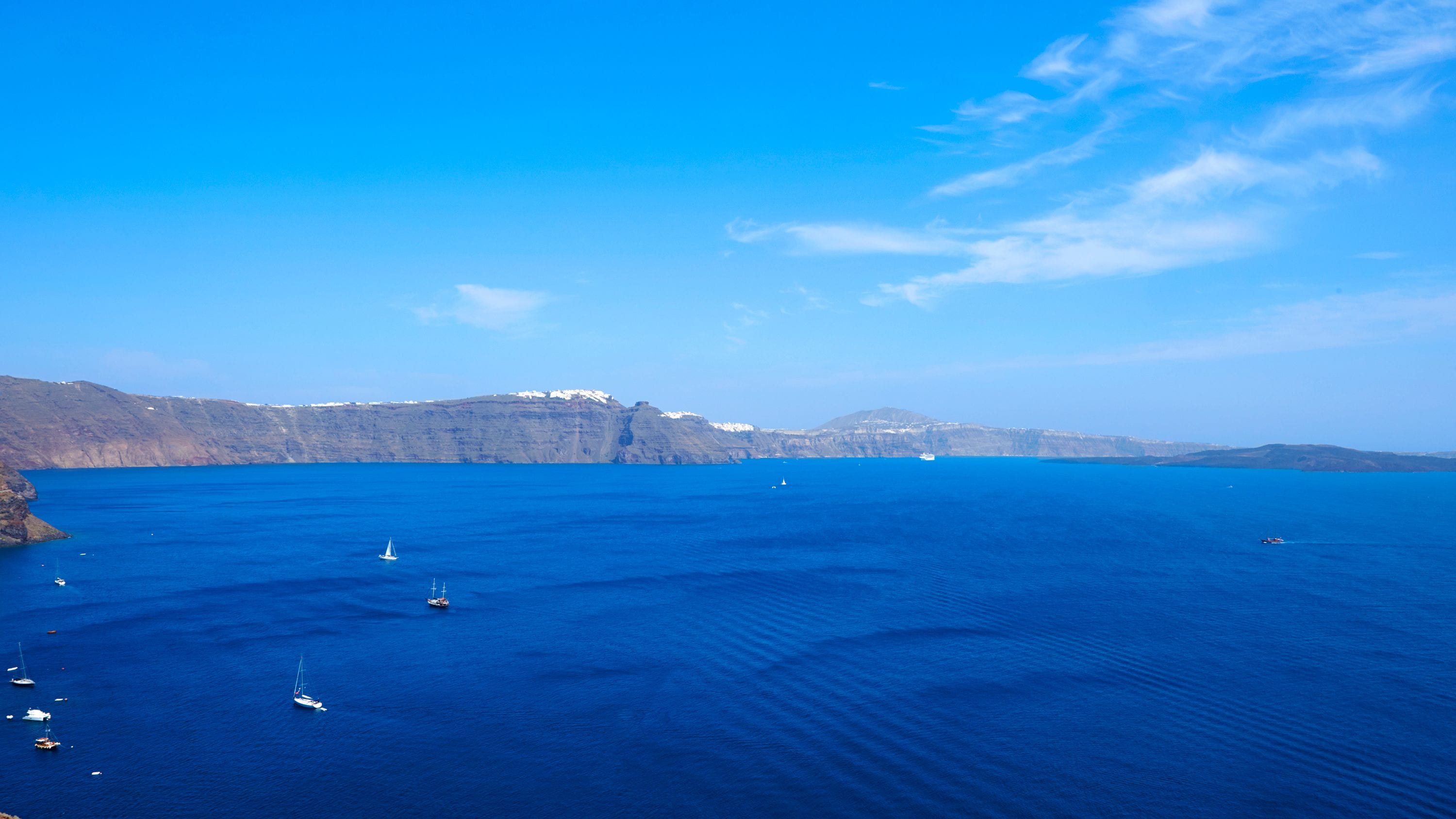 Eine Küstenlandschaft mit klarem, blauem Meer, felsigen Klippen und Booten.