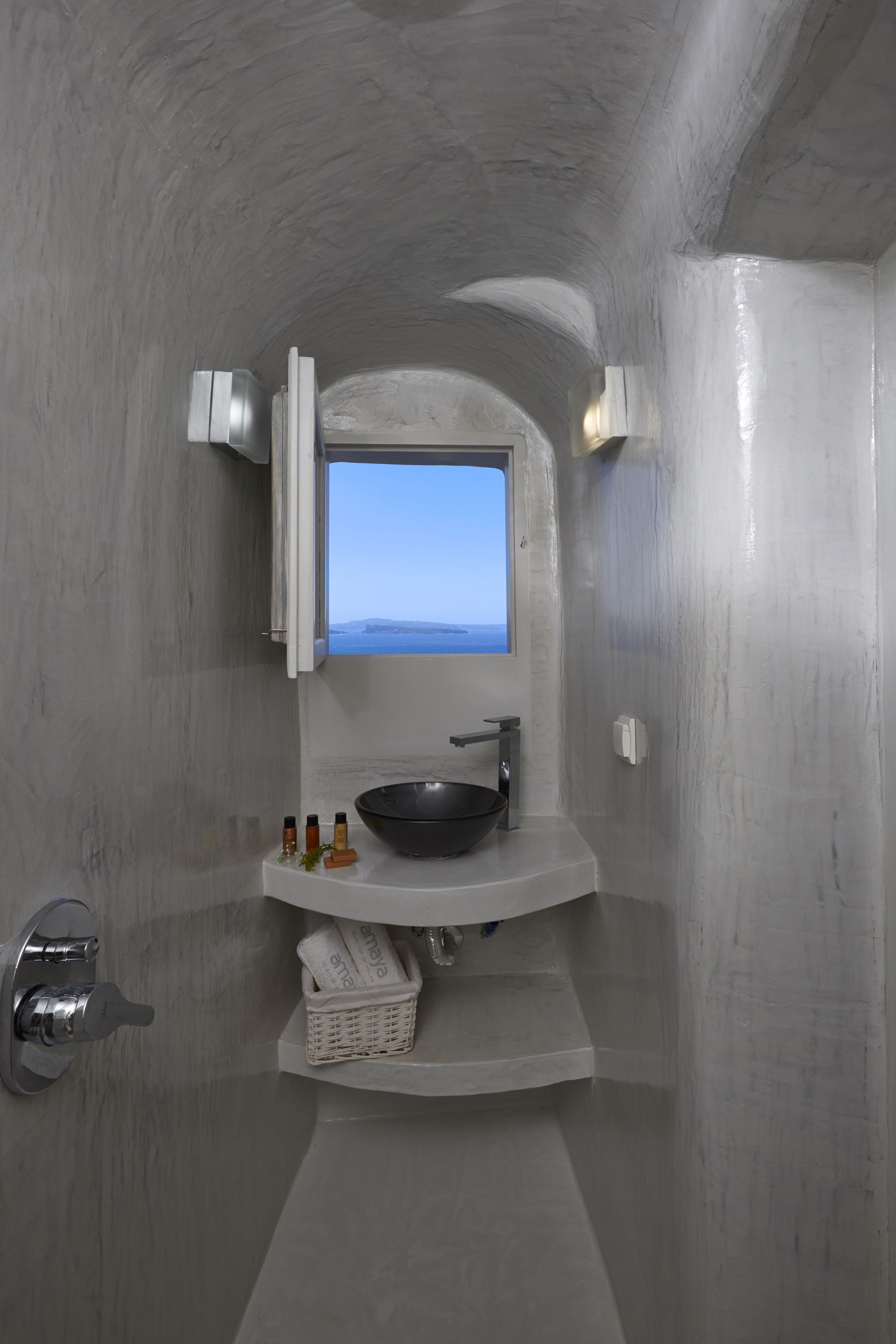 Un baño con un ventanal grande, un lavabo negro y un lavamanos blanco.