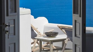 Puerta abierta que da a una terraza con vistas al mar y a las montañas.