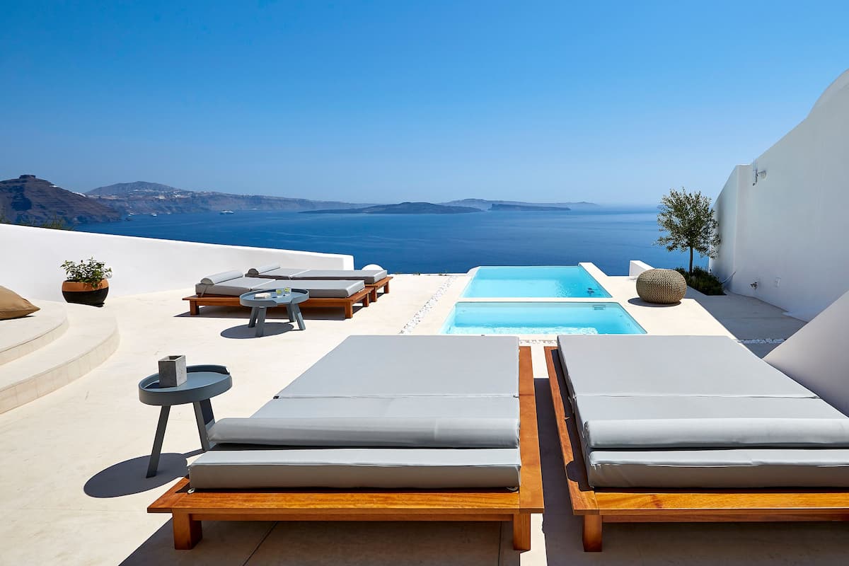 A rooftop terrace with two lounge chairs, a small table, and a rectangular pool.