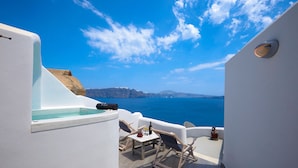 Una terraza soleada con piscina, sillones de descanso, una mesa con copas de vino y vistas al mar y a los acantilados.