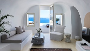 Una sala de estar moderna con un sofá blanco, una mesa redonda y vistas al mar a través de amplios ventanales.