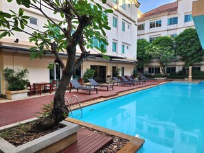 A swimming pool with lounge chairs and a small garden area. - Avion Hotel (Bangkok)