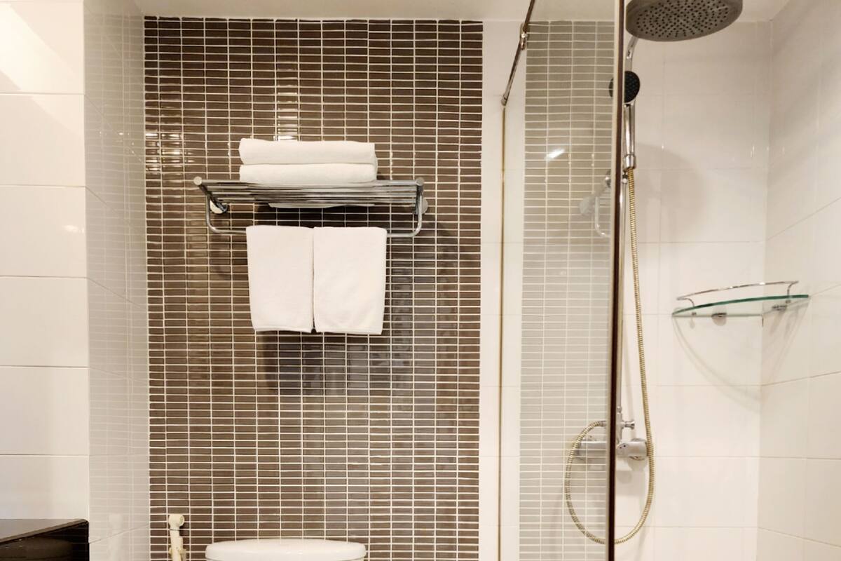 A modern bathroom with a toilet, a shower, and a glass shelf.
