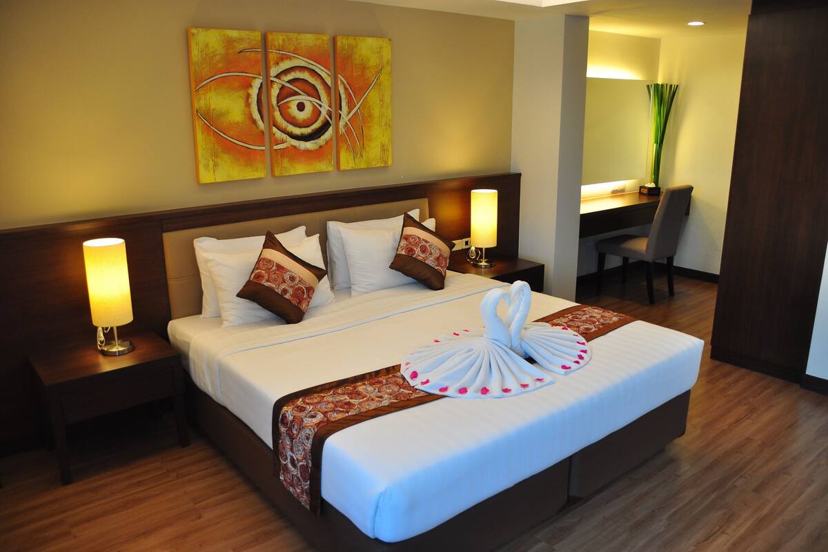 A hotel room with a large bed, two bedside tables with lamps, a desk, and a chair.