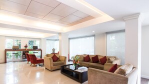 A spacious living area with a sofa set, a coffee table, and a desk with a laptop. - Avion Hotel (Bangkok)