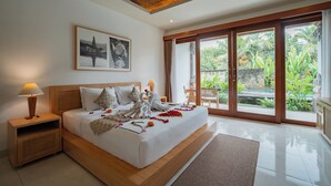 Quarto de hotel moderno com cama grande, cabeceira de madeira, duas mesas de cabeceira, um criado-mudo, uma janela ampla com vista para vegetação e teto com design em madeira.
