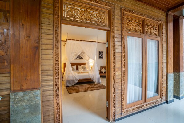 Traditional-style room with a large bed featuring a canopy, ornate paneling, and a large window.
