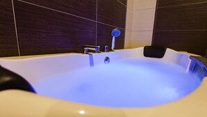 A modern bathroom with a freestanding bathtub, a handheld showerhead, and a built-in faucet. - Lavender Inn Permas Jaya (Masai)