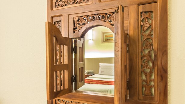 A wooden-framed mirror reflecting a room with a bed, a nightstand, and a painting on the wall. - Lavender Inn Permas Jaya (Masai)