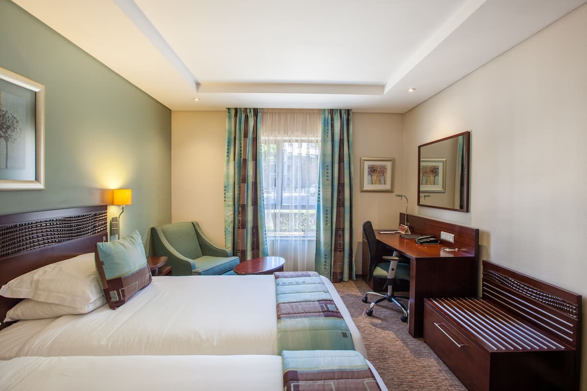 A hotel room with a bed, a desk, a chair, and a small table.