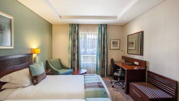Une chambre d’hôtel avec un lit, un bureau, une chaise et une petite table.