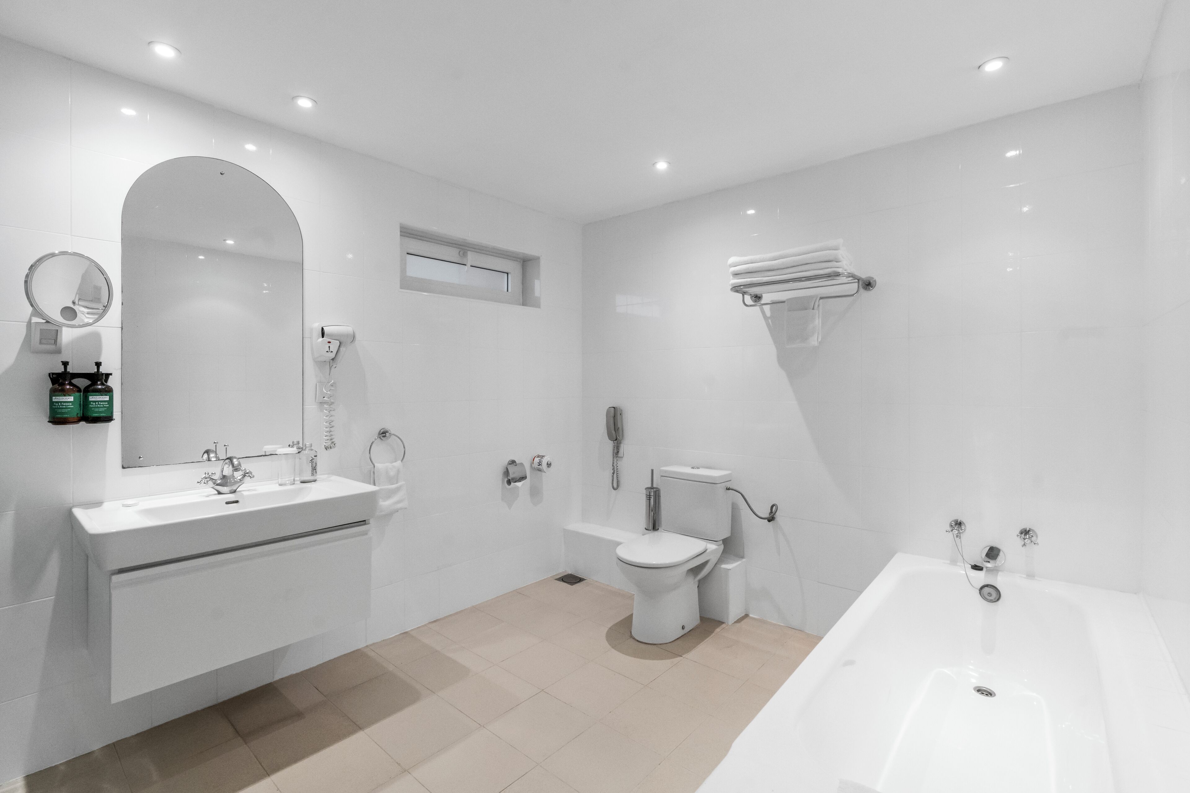 Une salle de bain moderne avec un grand miroir, un lavabo, des toilettes et une baignoire.