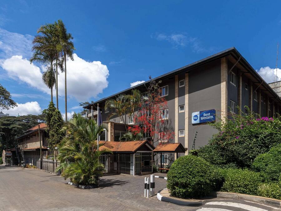 A multi-story hotel with a prominent "Best Western" sign, a gated entrance, and a well-maintained outdoor area with palm trees and shrubs.