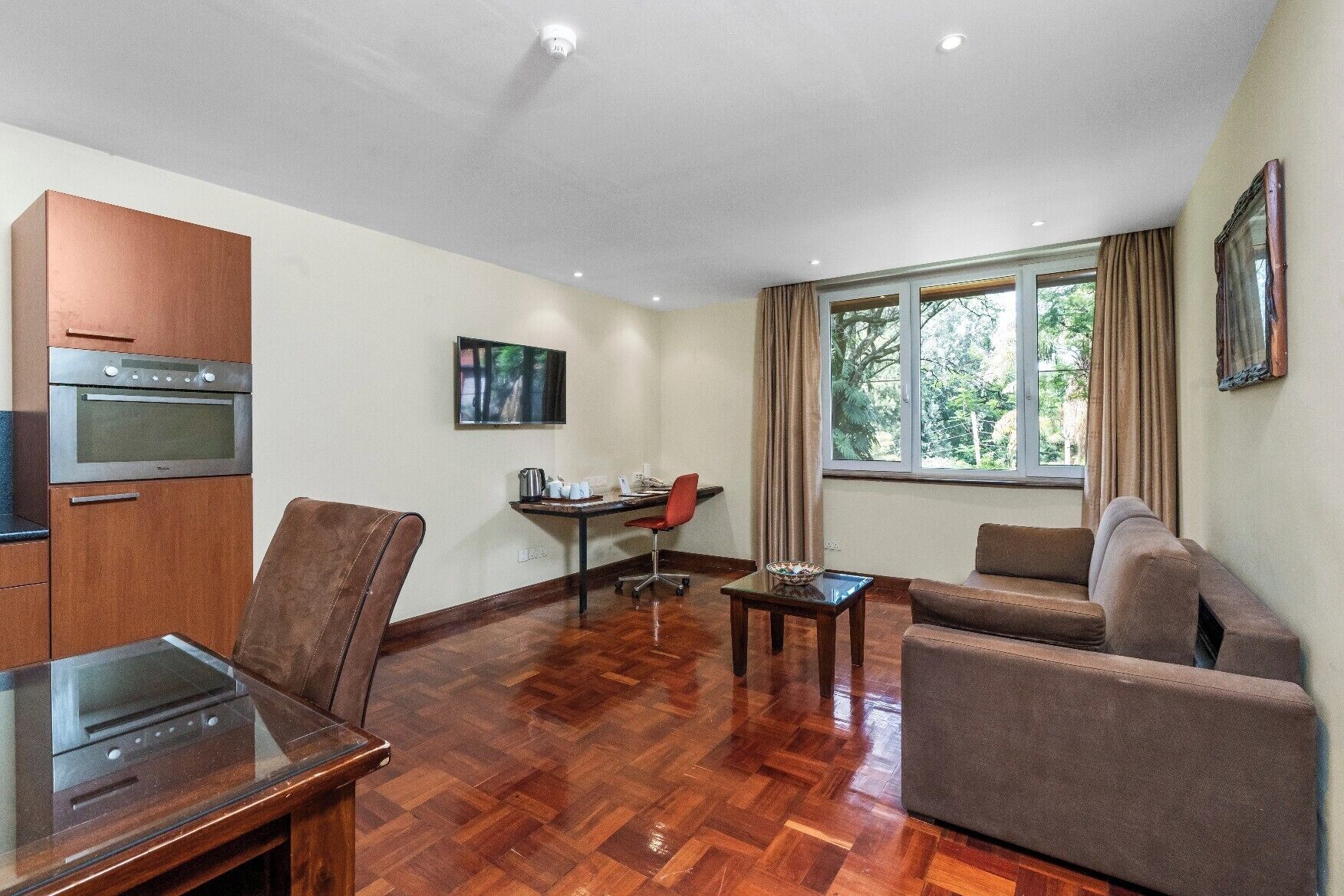 A modern living room with a sofa, a dining table, and a kitchen area with an oven.