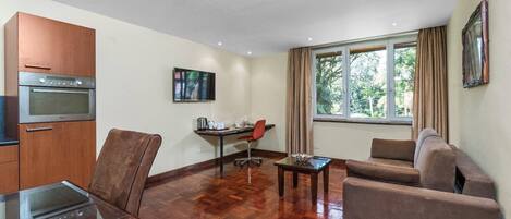 A modern living room with a sofa, a dining table, and a kitchen area with an oven.