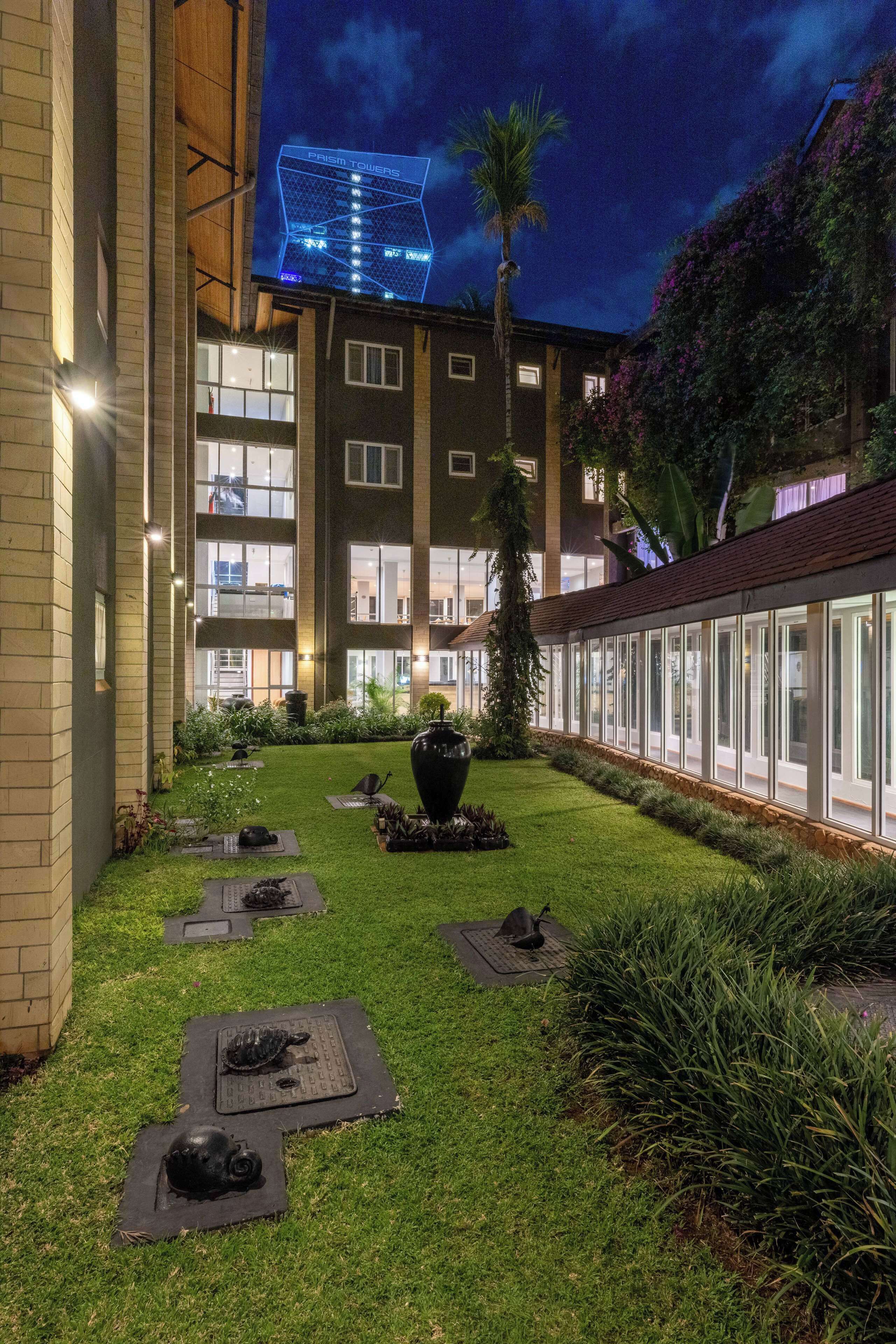 Un patio con césped cuidado, mobiliario exterior y un edificio con ventanas grandes y un letrero visible.