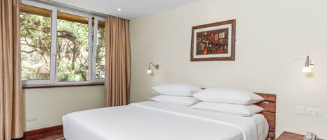 Un dormitorio con una cama de madera, una ventana con cortinas, un cuadro en la pared y una mesita de noche con lámpara.