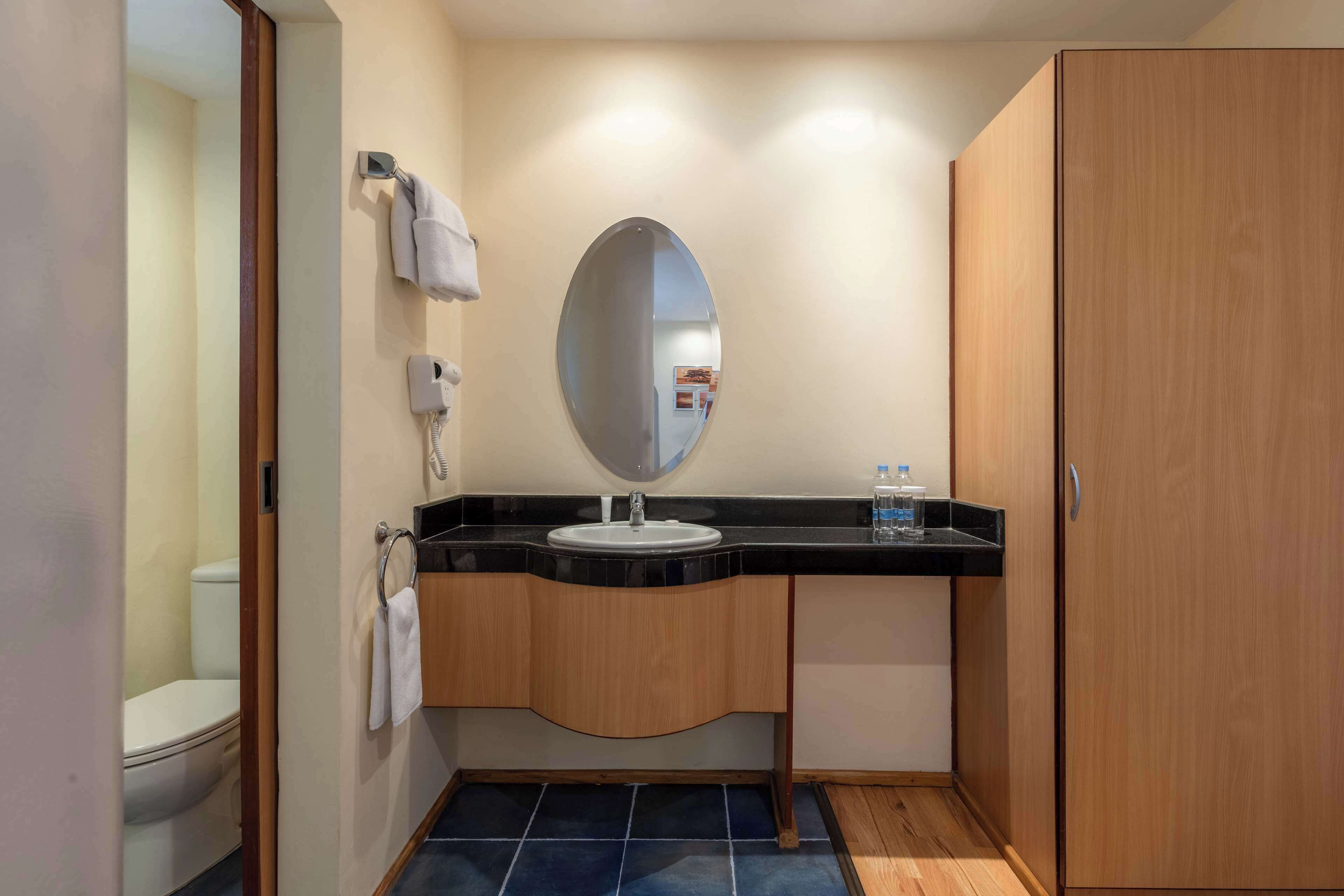 Ein Badezimmer mit Toilette, Waschbecken, Spiegel, Handtuchhalter und Schrank.