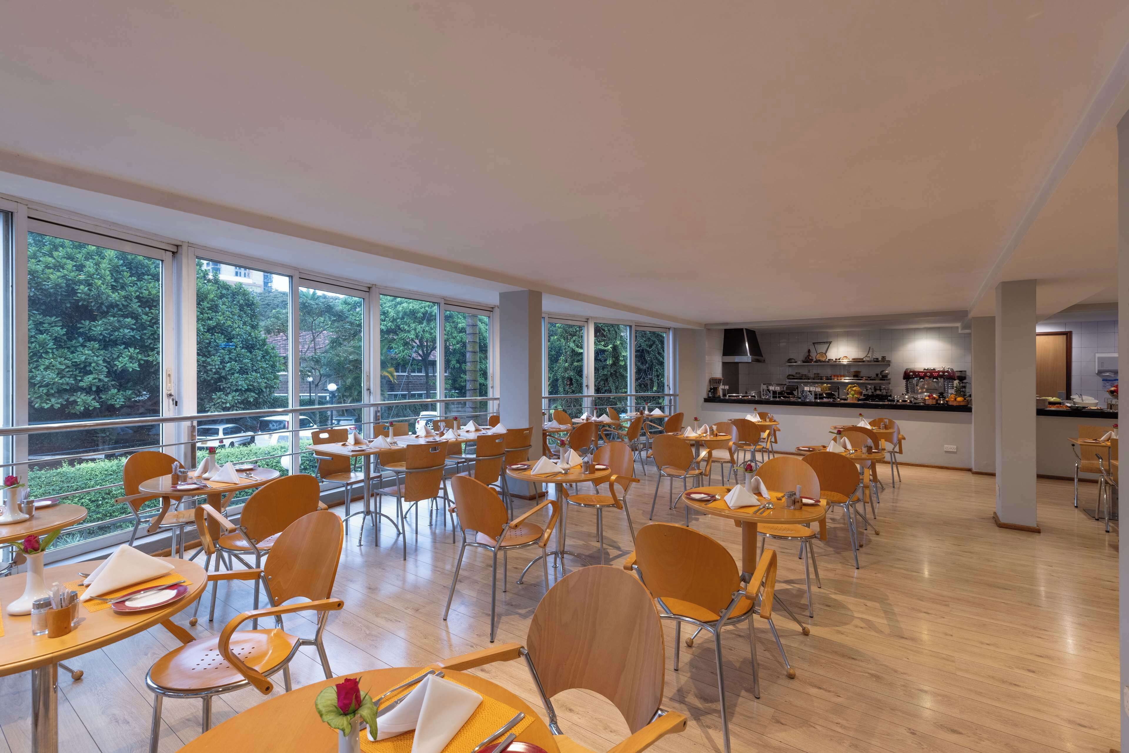 A spacious dining area with large windows, wooden tables, and chairs.