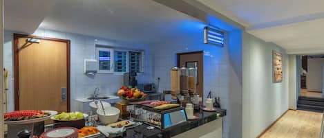 A hotel kitchen with a buffet setup, including various food items and a coffee station.