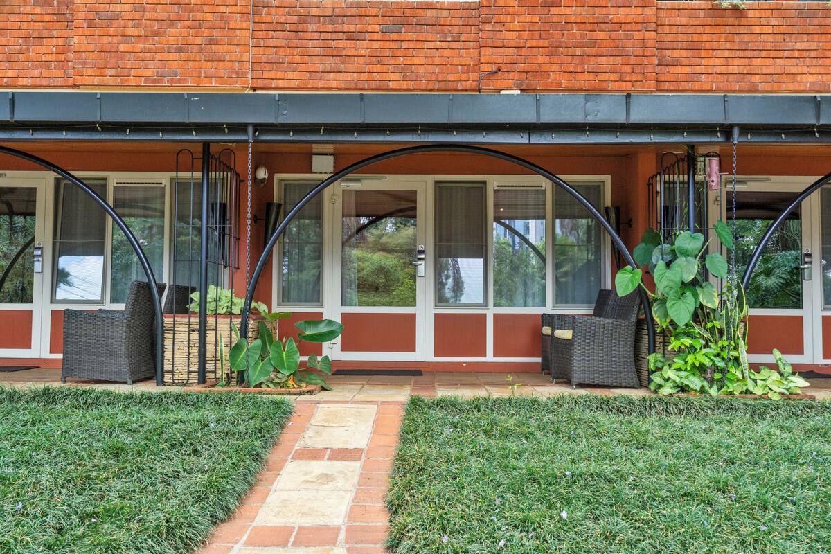 Een bakstenen gebouw met een overdekte patio, zitplaatsen buiten en een kleine tuin.