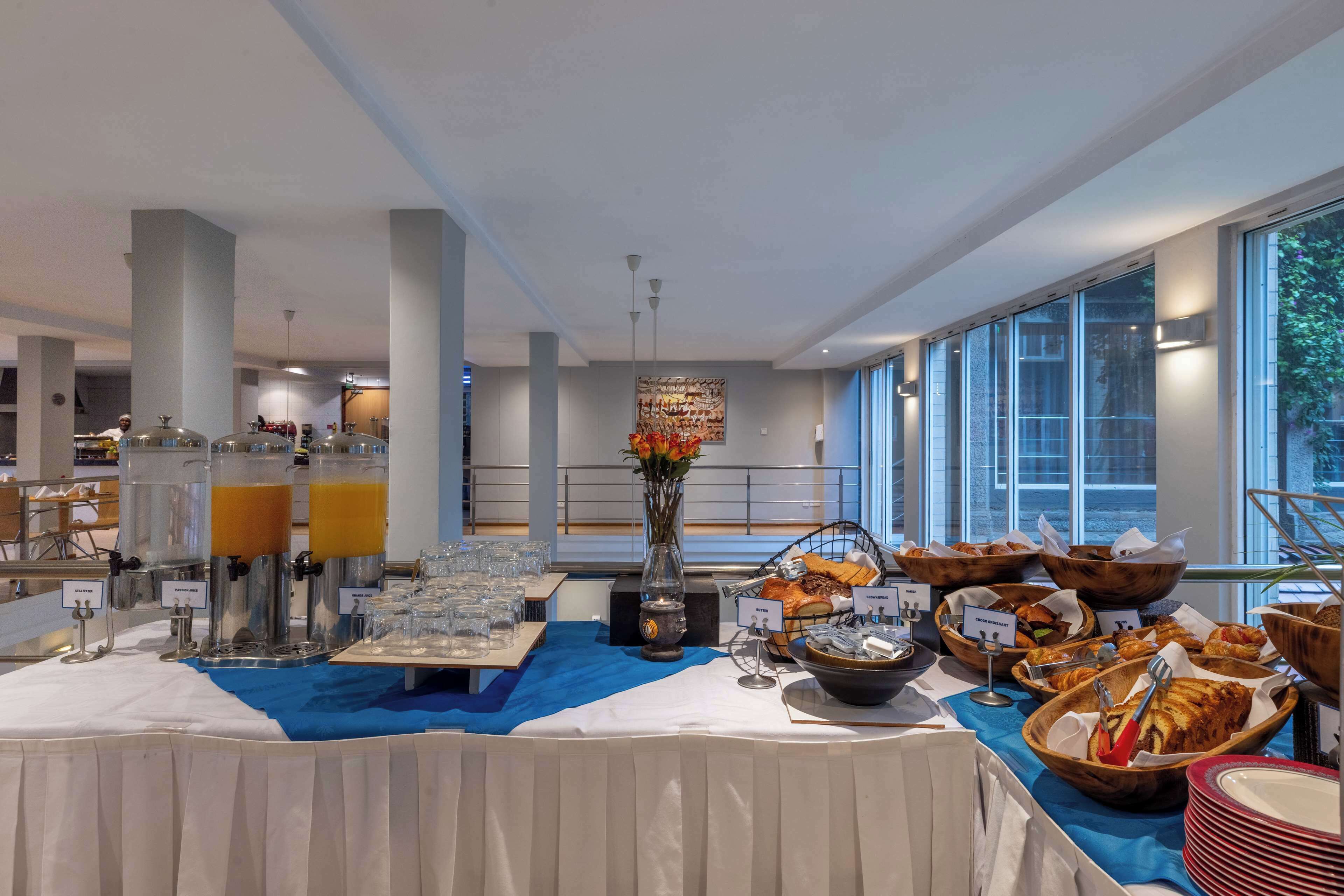 A buffet setup with multiple food stations, including a fruit juice dispenser, a candle centerpiece, and various food containers.