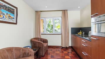 Una cocina compacta con zona de comedor, suelo de madera y una ventana con cortinas.