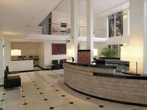 Un hall amplio con una recepción de diseño curvo, una zona de estar y un ventanal con vistas.