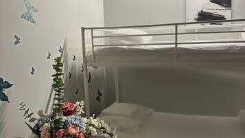Dormitorio con literas, una mesita pequeña y un jarrón con flores.