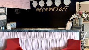 A reception area with a black wall, clocks indicating different cities, and two red chairs. - Arkadia Hotel & Hostel (Helsinki)