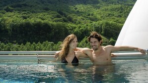 Un couple dans une piscine, avec un paysage montagneux en arrière-plan.