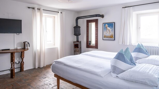 Une chambre d’hôtel avec un lit, un bureau, une télévision et une fenêtre avec des rideaux.