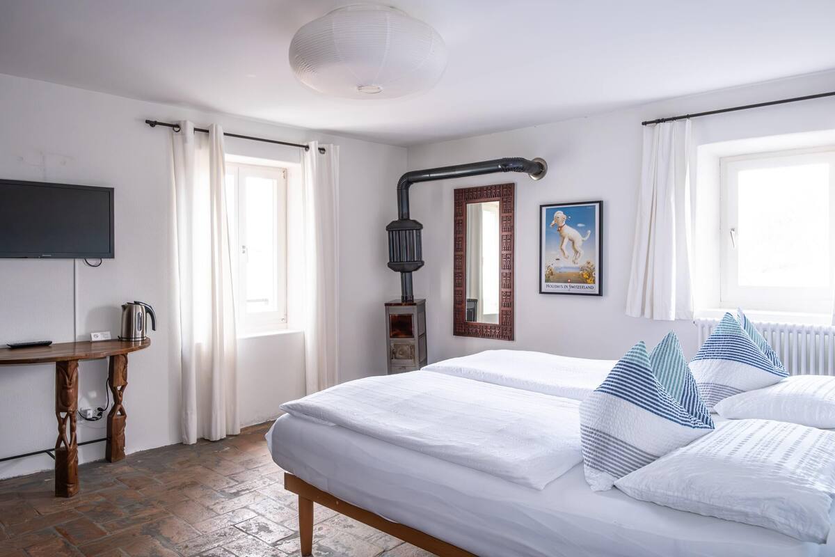 Una habitación de hotel con una cama, un escritorio, un televisor y una ventana con cortinas.