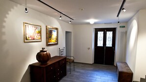 Un couloir avec un banc en bois, une armoire et deux œuvres d’art encadrées accrochées au mur.