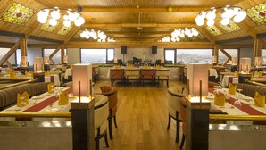 A restaurant with a high wooden ceiling, large windows, and multiple dining areas. - Dolphin Hotel (Visakhapatnam)