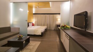 A hotel room with a bed, a sofa, a TV, a desk, and a window with curtains. - Dolphin Hotel (Visakhapatnam)