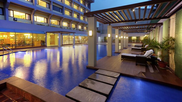 An indoor swimming pool with lounge chairs and a covered seating area. - Dolphin Hotel (Visakhapatnam)