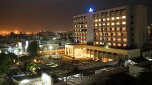 A multi-story hotel with a prominent sign, a parking area, and surrounding urban buildings. - Dolphin Hotel (Visakhapatnam)