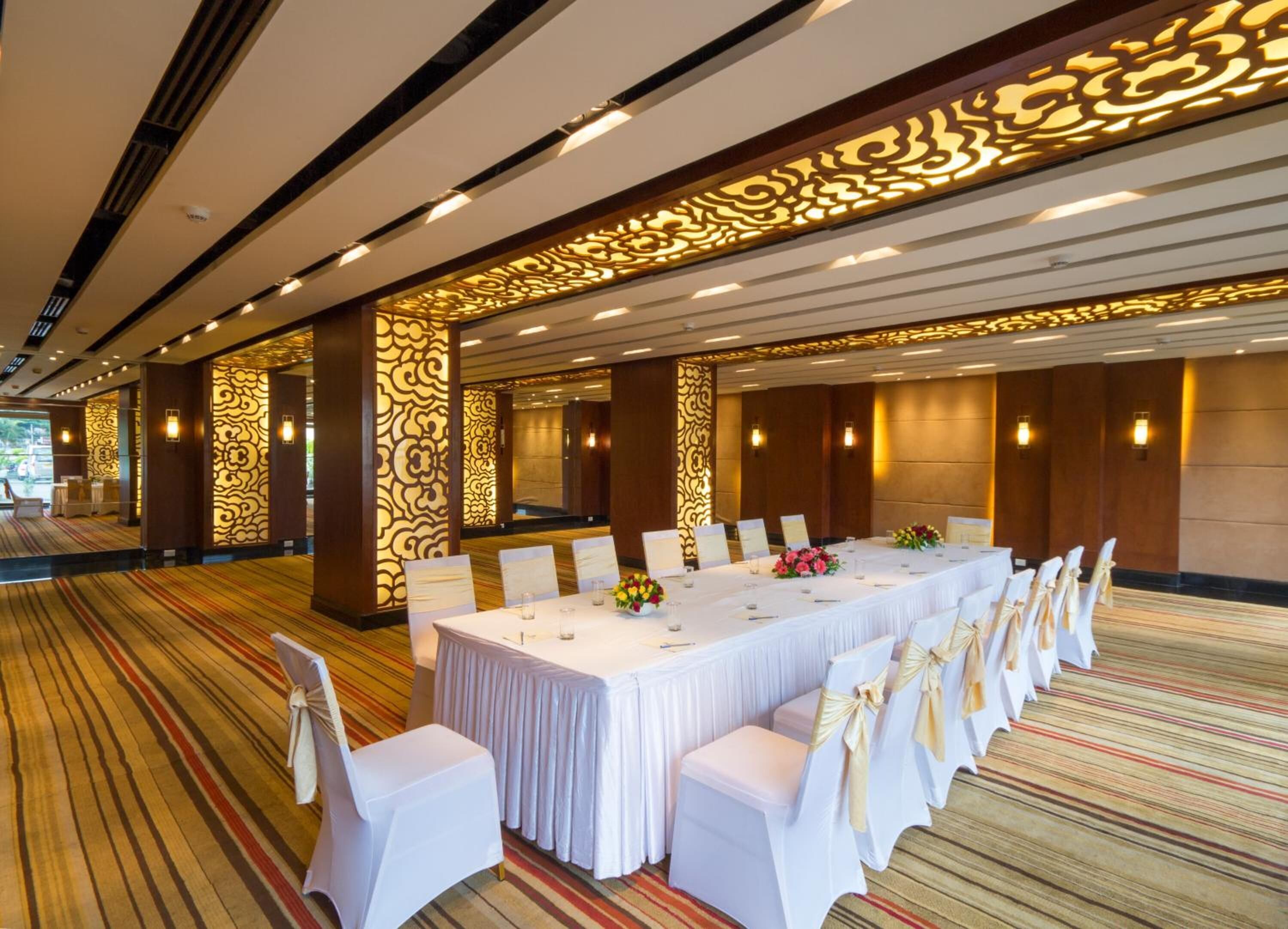 A conference room with a long table, white chairs, and decorative wall panels.