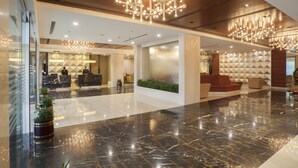 A modern lobby with a marble floor, a reception desk, and a seating area with a geometric wall design. - Dolphin Hotel (Visakhapatnam)