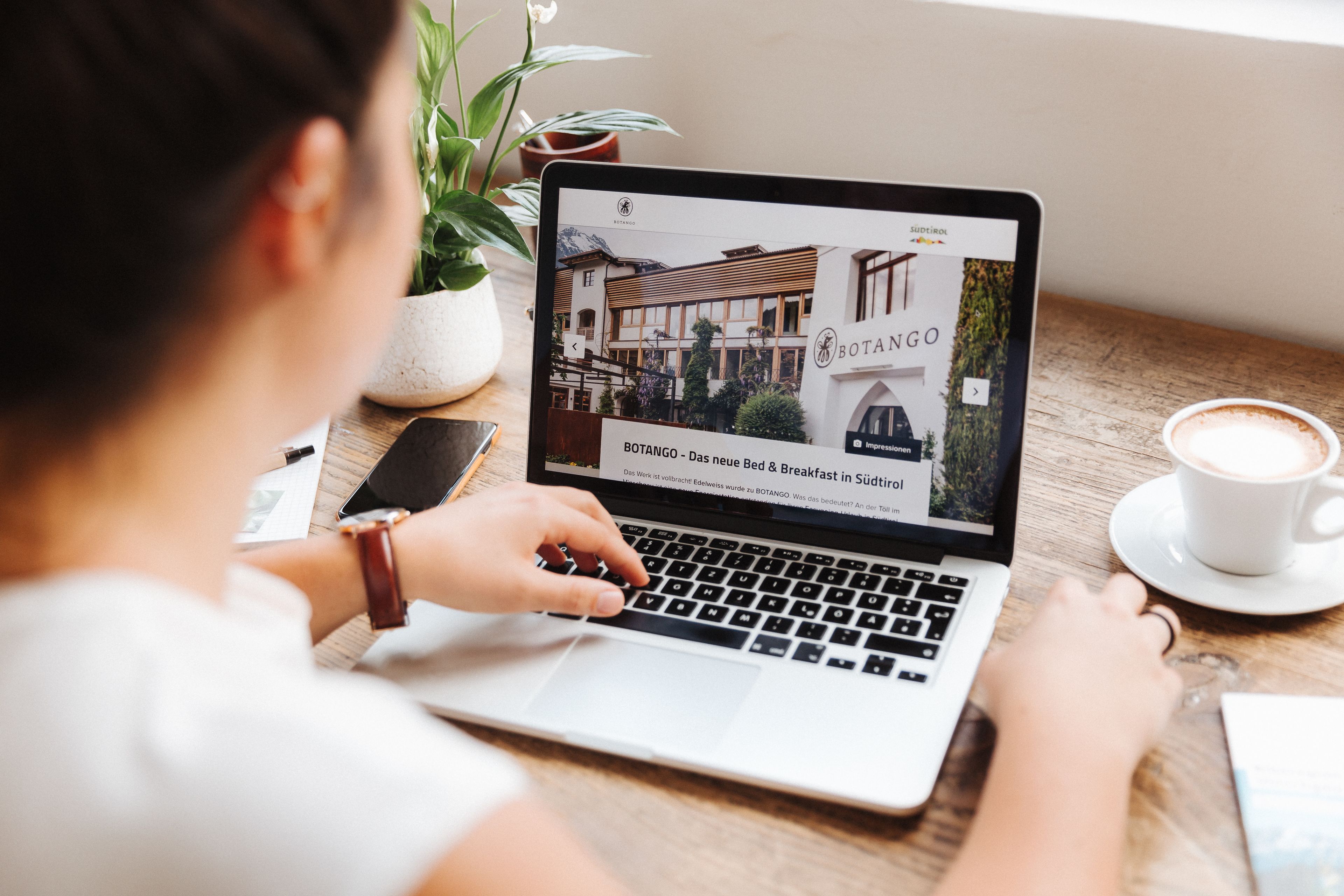 Uma pessoa usando um laptop com uma página da web aberta mostrando um edifício chamado 'BOTANGO'.