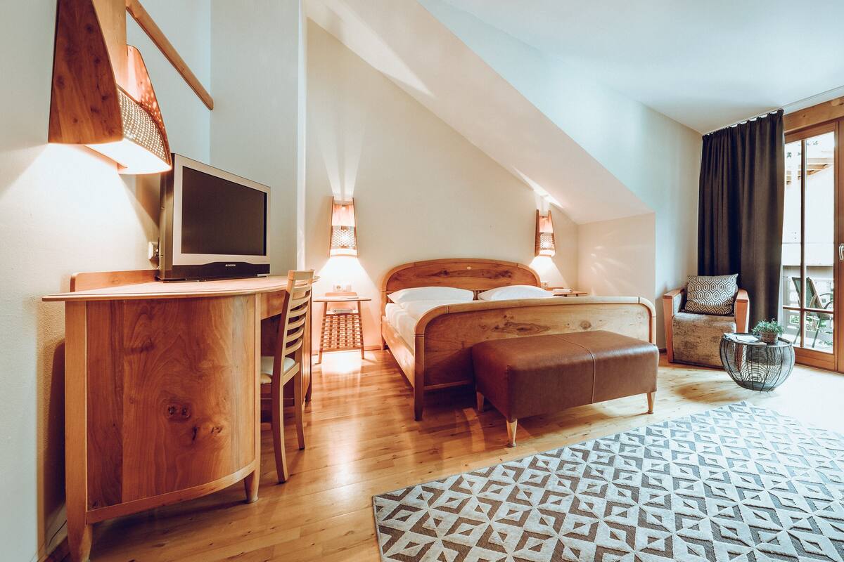 A bedroom with a bed, bedside table, lamp, and a TV.