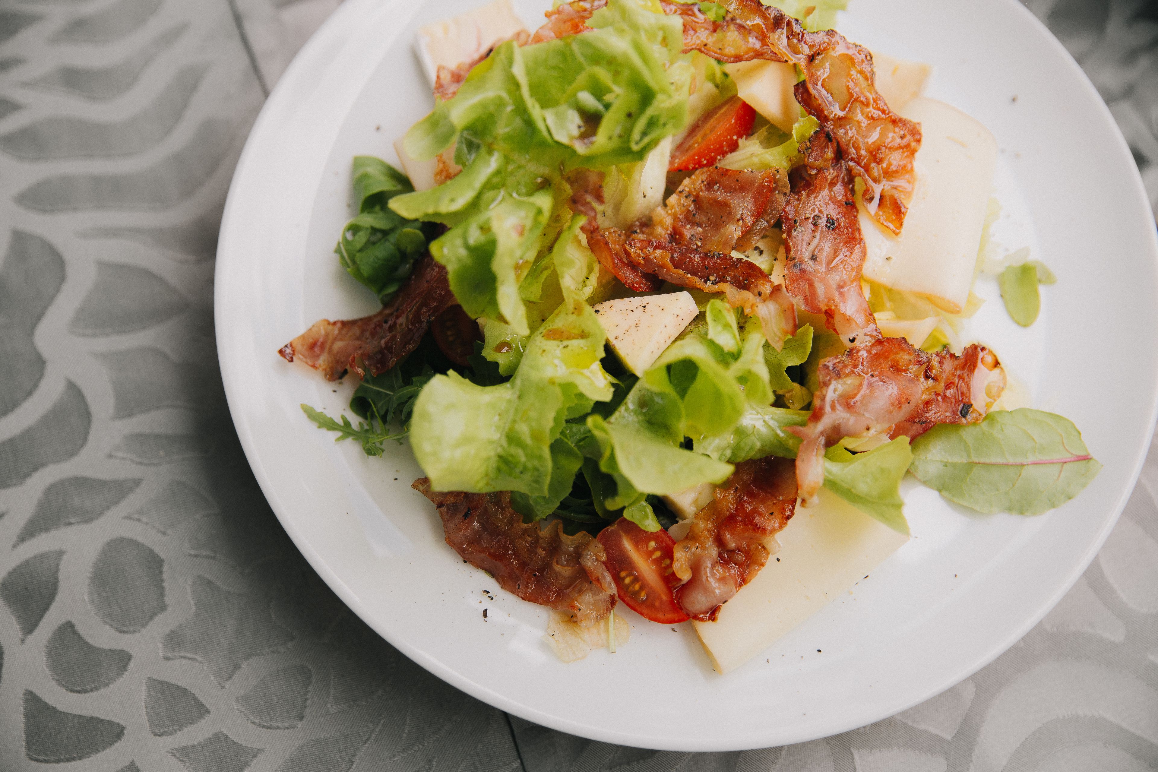 A plate of food with lettuce, tomatoes, cheese, and bacon.