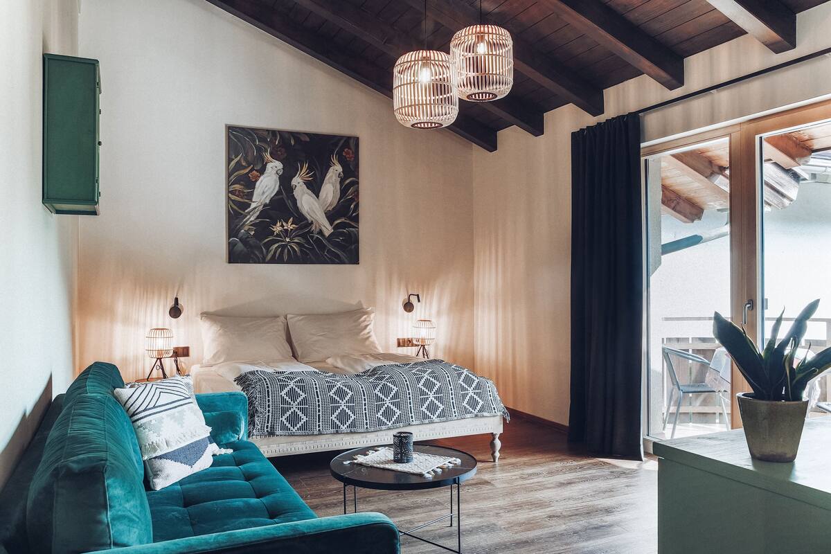 A bedroom with a bed, a sofa, a coffee table, and a potted plant.