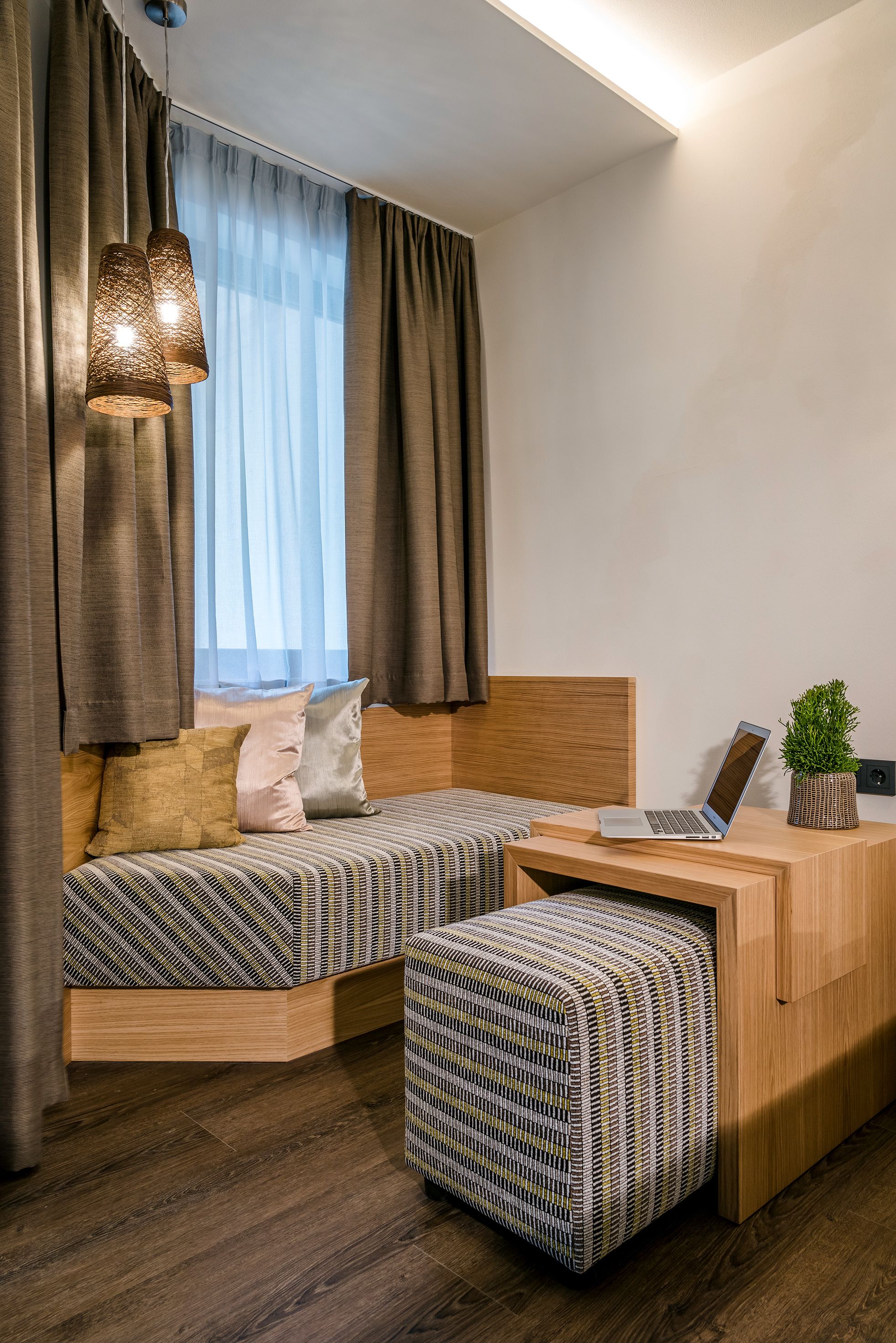 Une chambre à coucher moderne avec un lit en bois, un petit bureau avec un ordinateur portable et une plante en pot.