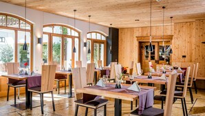 Een restaurant met houten inrichting en grote ramen. Er staan tafels klaar met stoelen en servies.