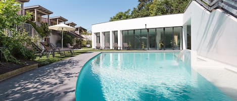 Una piscina cubierta, una piscina al aire libre de temporada, sombrillas