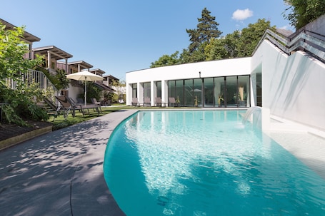 Una piscina techada, una piscina al aire libre de temporada, sombrillas